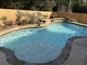 Freeform pool with stone decking and a waterfall
